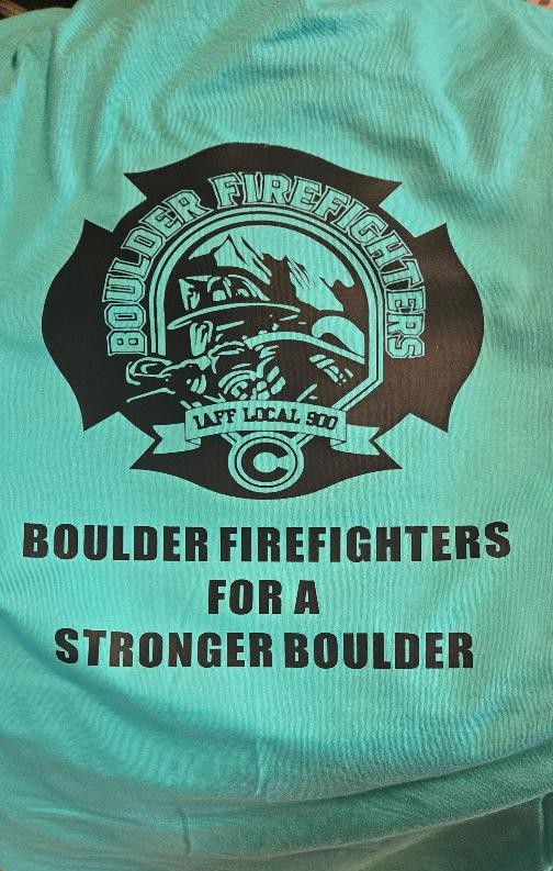 Completed turquoise Boulder Firefighters shirt with a large black firefighter graphic and supporting text