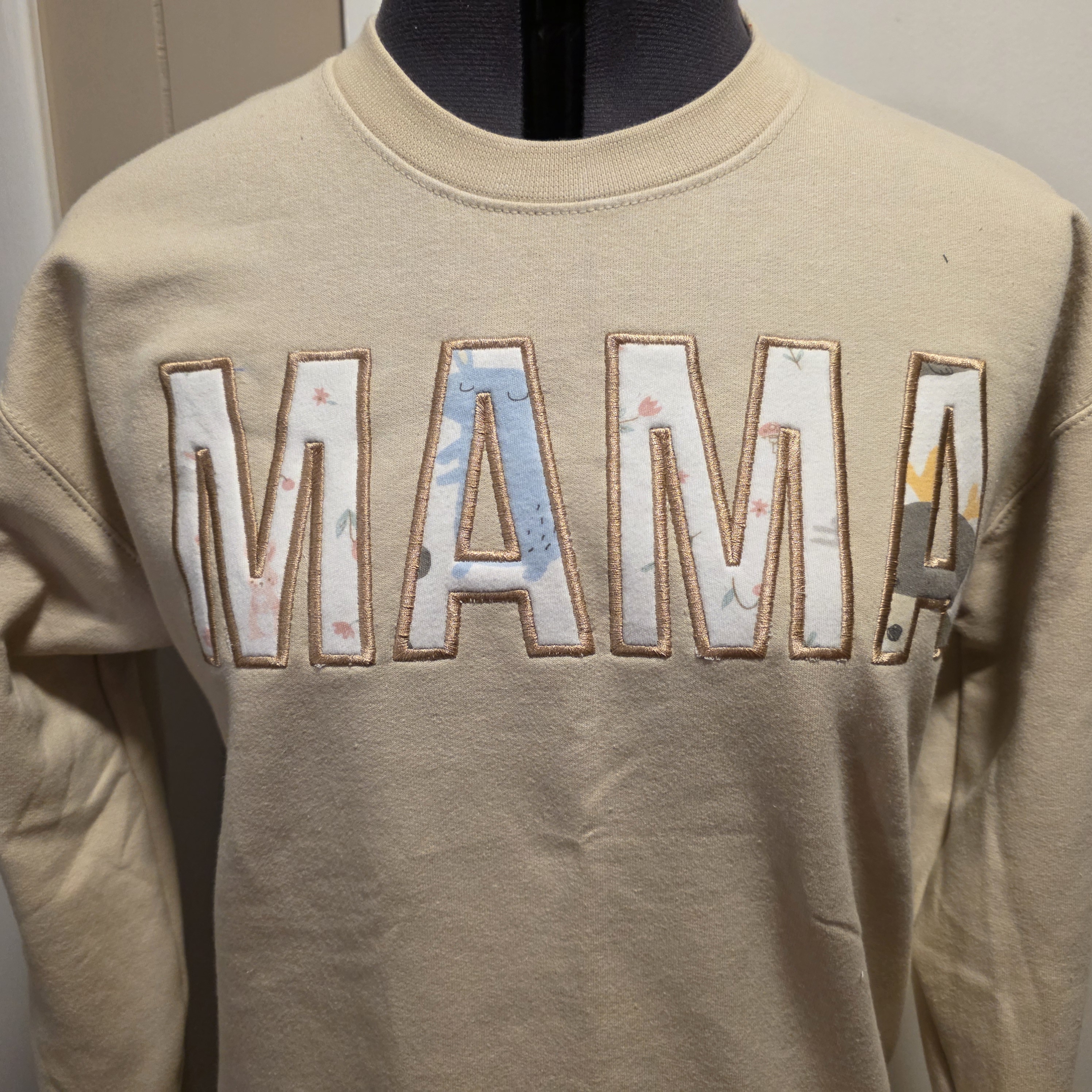 Completed MAMA sweatshirt with patterned appliqué letters and embroidered finishing