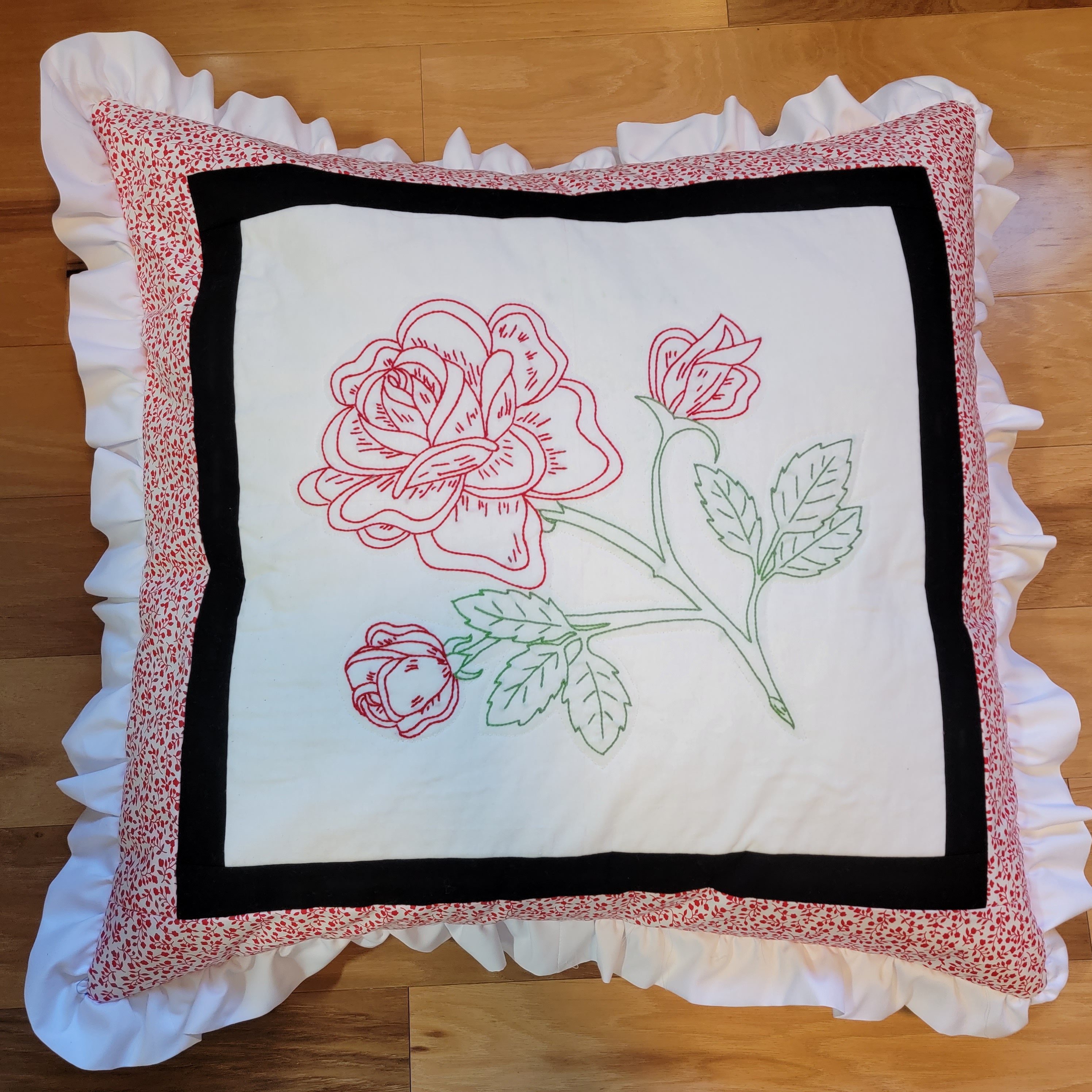 Completed embroidered rose pillow with decorative fabric and ruffled trim