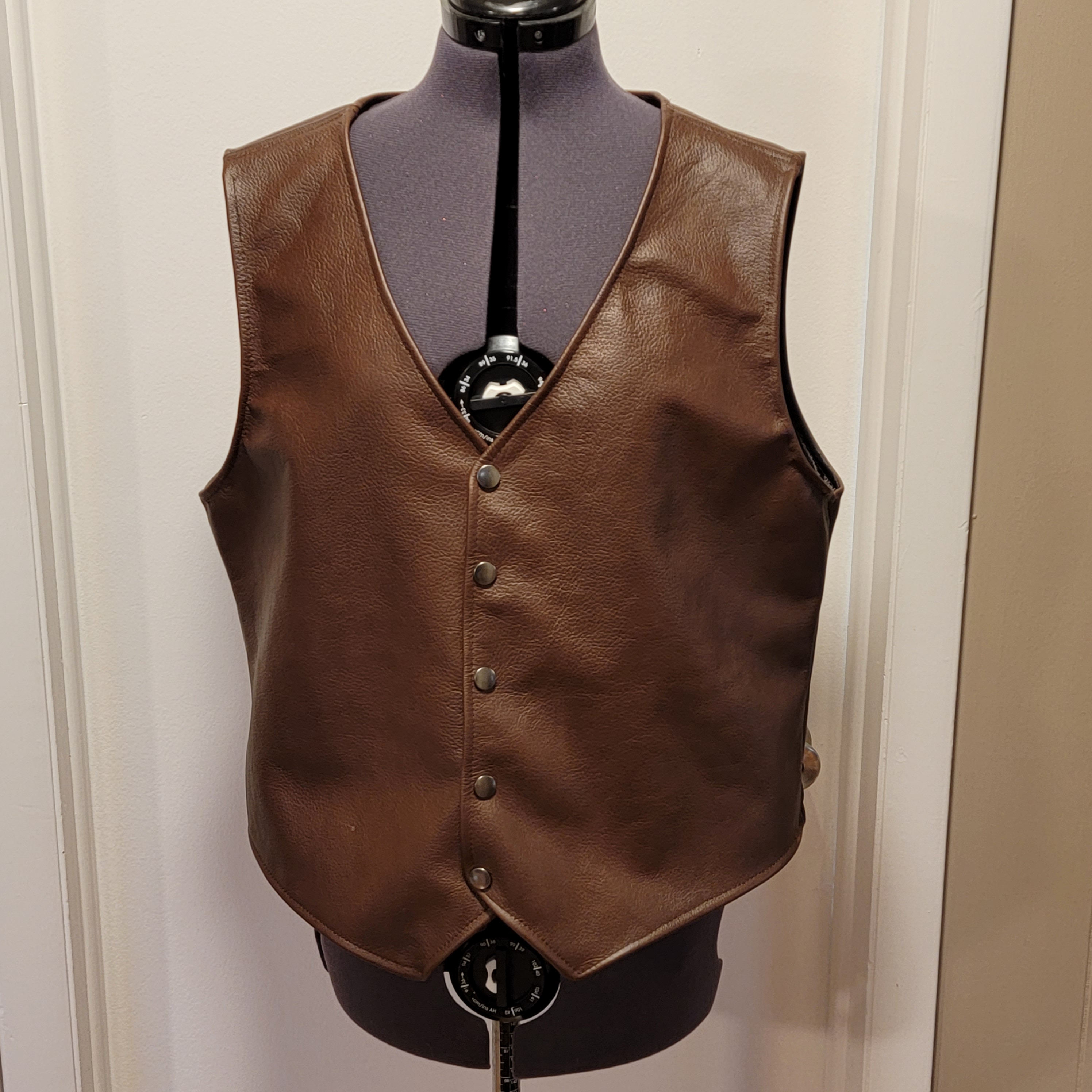 Completed custom leather vest with shaped panels and snap closures